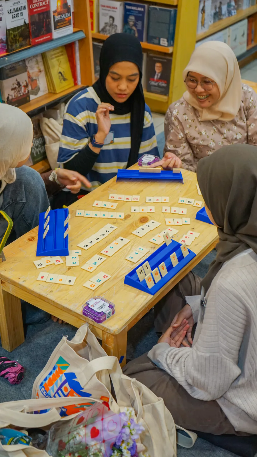 Two players leaning in over a Sequence board as an event host looks on