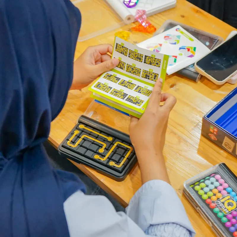 A young shopper flipping through a Smart Games puzzle booklet at a stockist