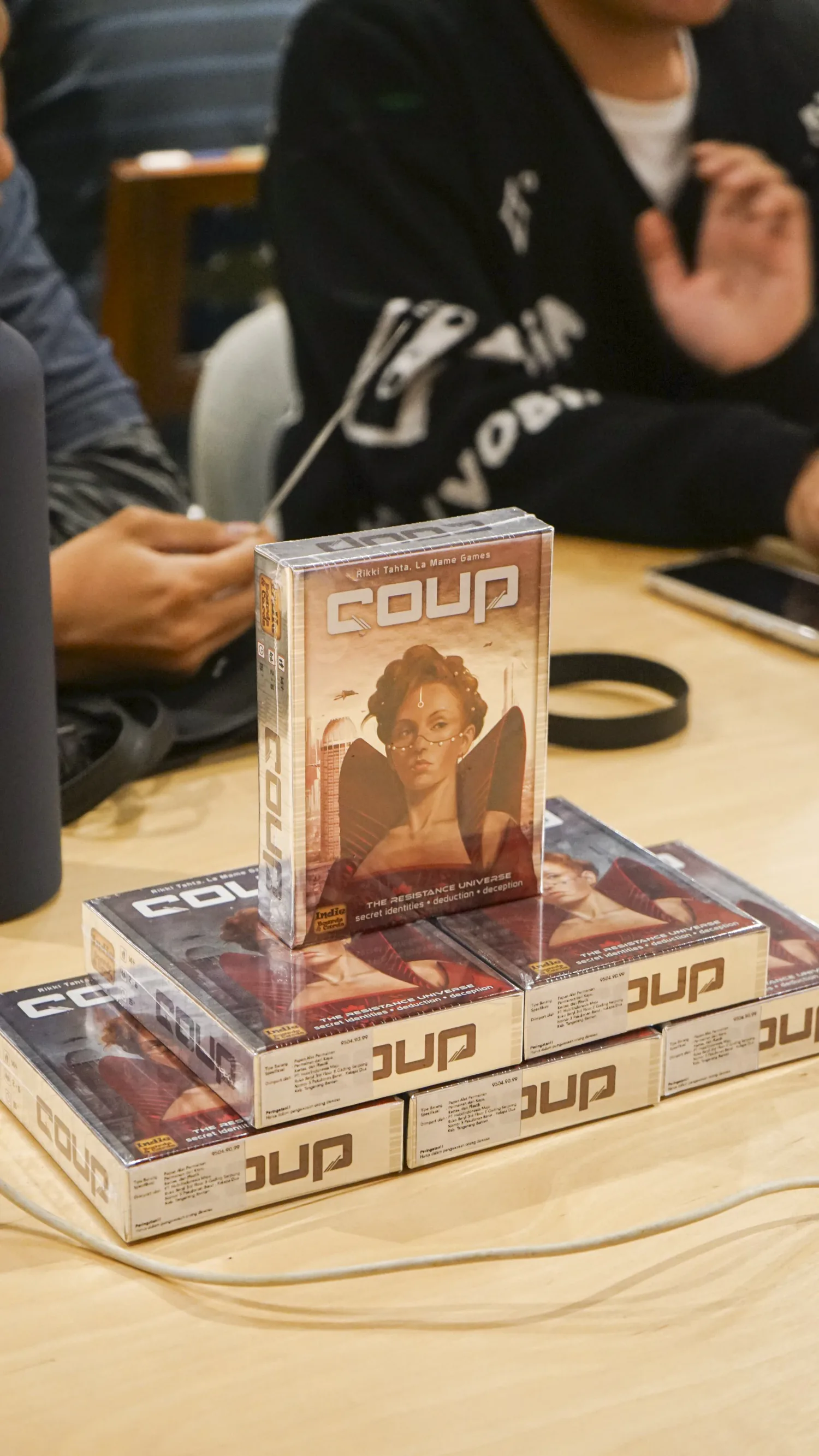 Fresh Coup stock stacked on a reseller demo table with players around it