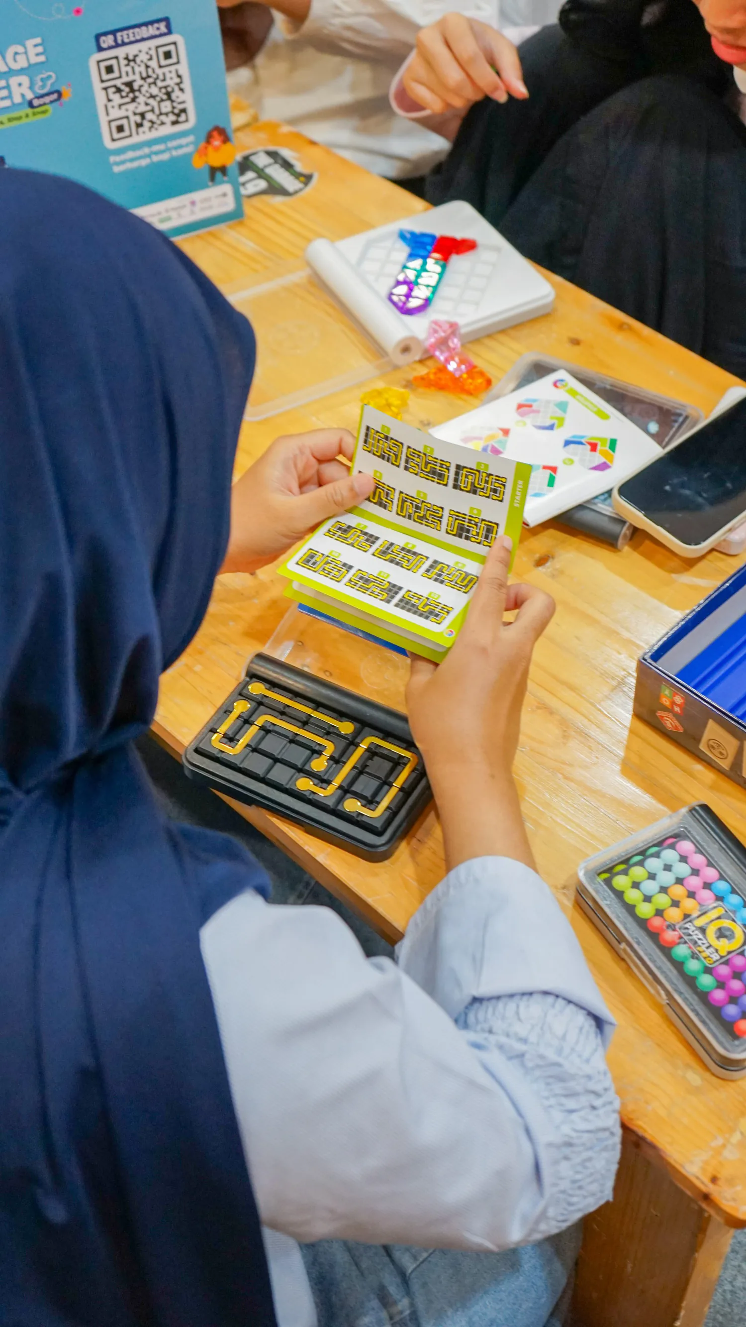 A young shopper flipping through a Smart Games puzzle booklet at a stockist